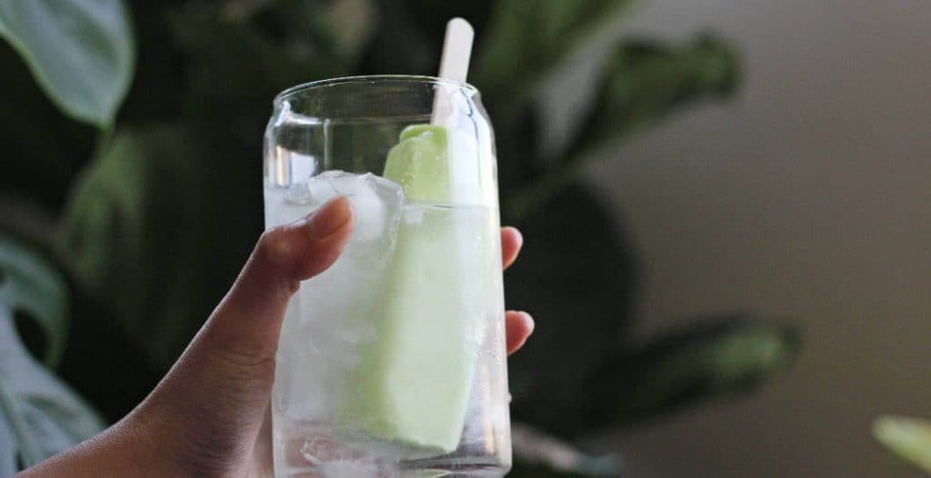 Clear glass with clear liquid and a pale green popsicle.