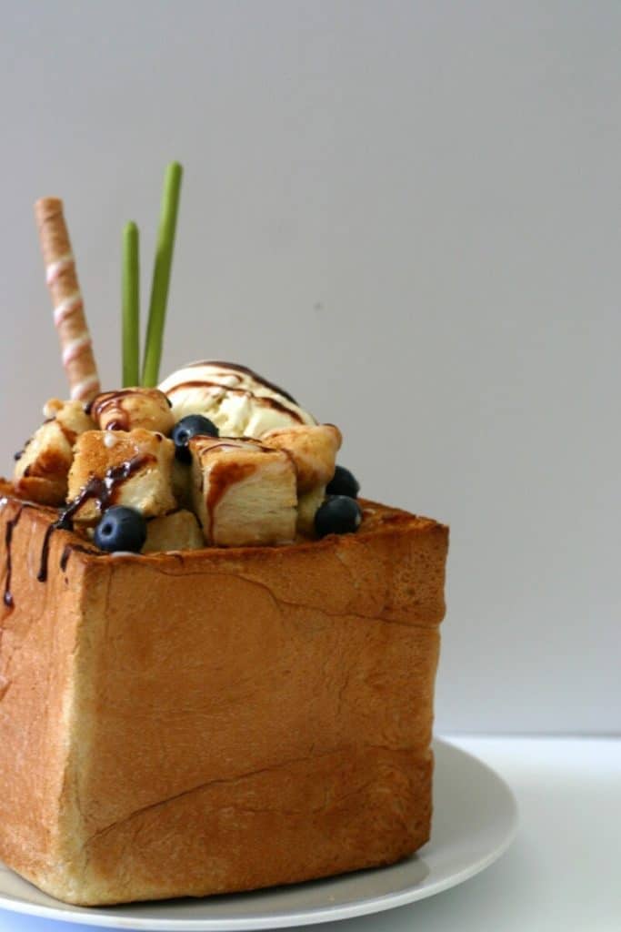 Close-up of all the fillings in this honey toast: ice cream, blueberries, cubed toast, matcha Pocky, cigar cookies and chocolate sauce. #honey #toast #icecream #dessert