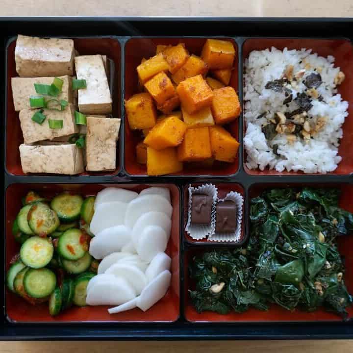 This bento box has rice, roasted squash, marinated tofu, garlicky cucumbers, pickled radish and sauteed kale, but you can definitely omit parts as you please! #bentobox #lunchideas #vegetarian