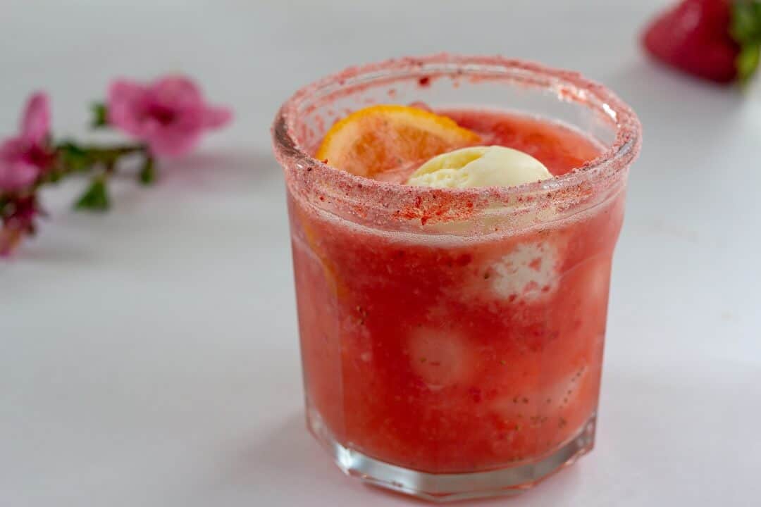 This strawberry citrus margarita float is delicious as is, but if you add some ground freeze dried strawberries to the rimming salt, you get another hit of fruity pink flavor! #strawberry #citrus #margarita #tequila