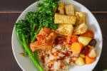 Bowl with rice, tofu, broccolini, kimchi, carrots and gochujang sauce.