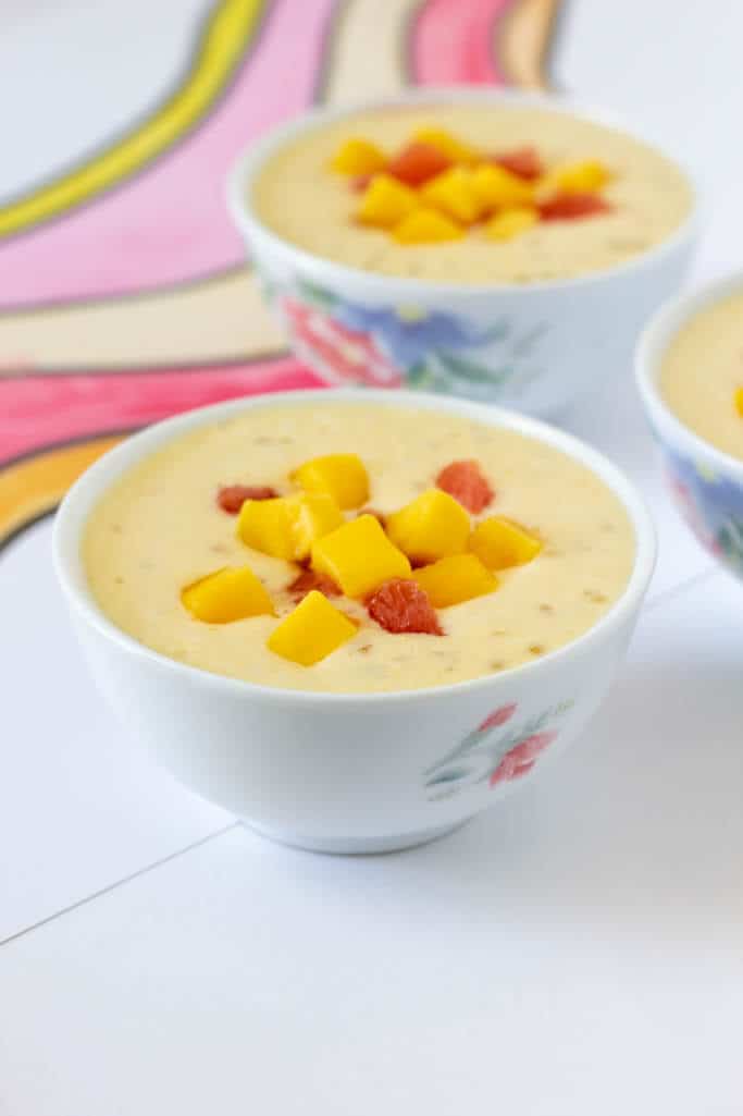 Three bowls full of creamy mango and coconut milk smoothie mixed with chewy sago pearls and sweet chunks of mango and pomelo.
