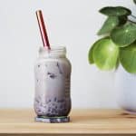 Glass jar filled with creamy maroon ombre colored red bean milk tea with a metal straw.