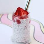 Clear glass filled with white tapioca pudding and bright red strawberry slush and sliced strawberries.