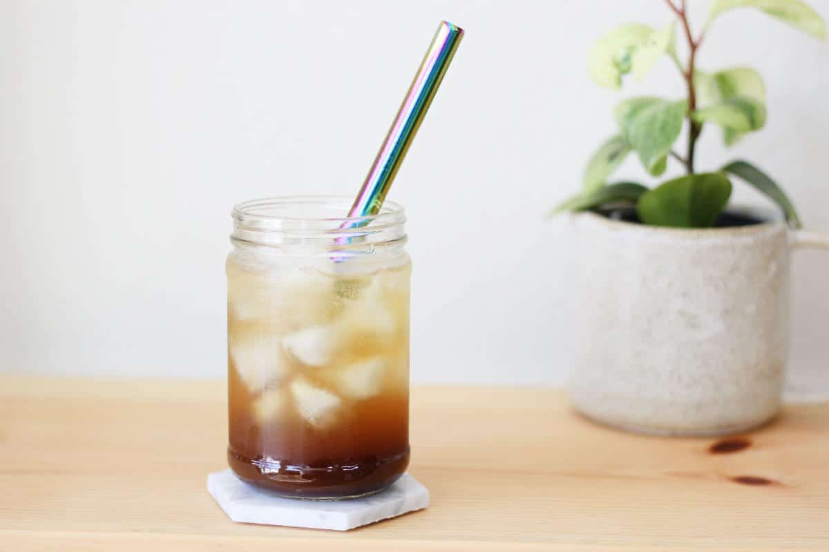 Clear glass filled with a shot of espresso and iced, then topped off with sparkling water and served with a metal straw.