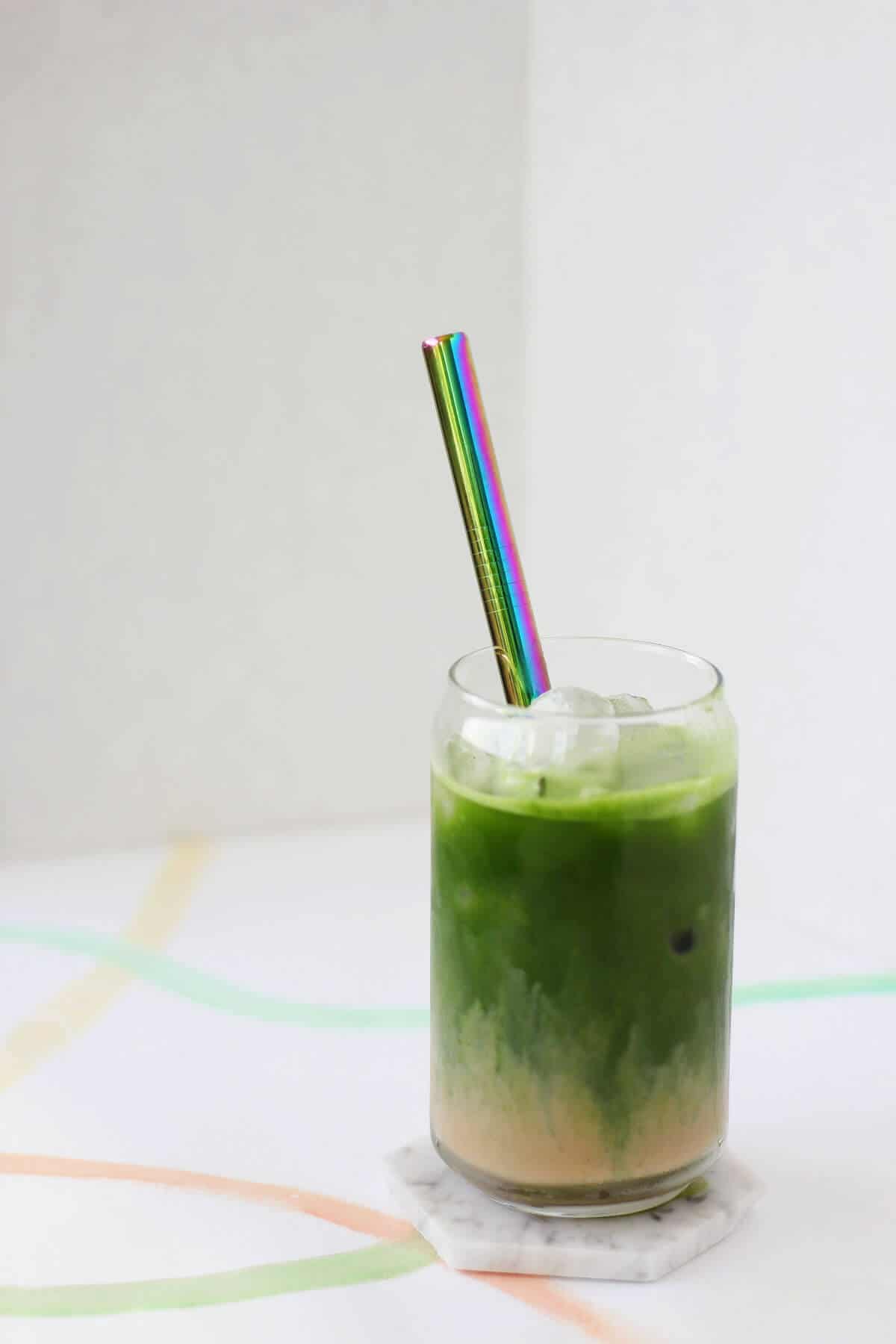 Clear glass filled with a layer of tan colored masala chai topped with bright green matcha.