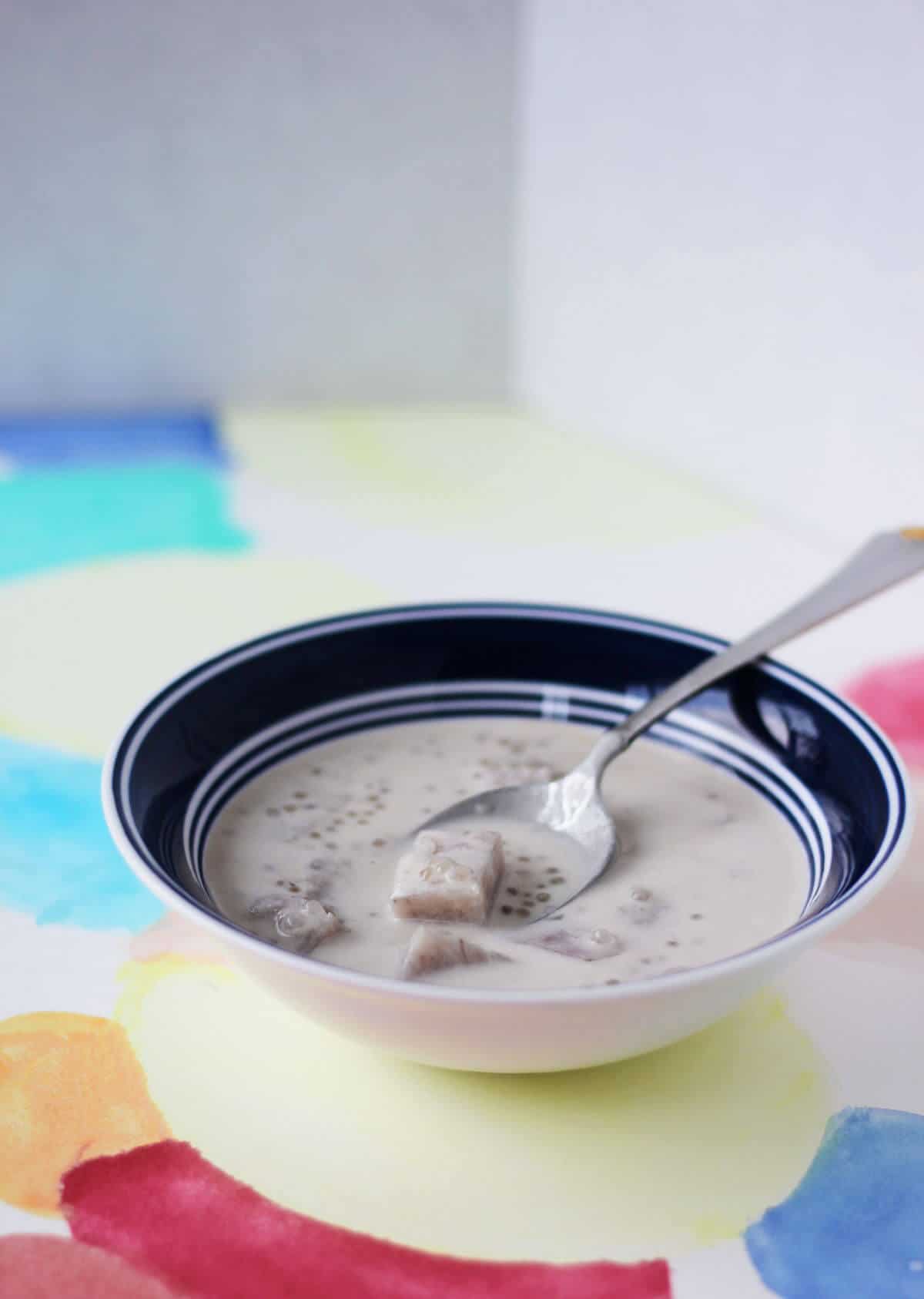 Bowl filled with coconut milk, lilac taro chunks and clear sago.