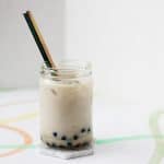 Clear glass filled with brown sugar boba and tan colored wintermelon milk tea with a metal straw.
