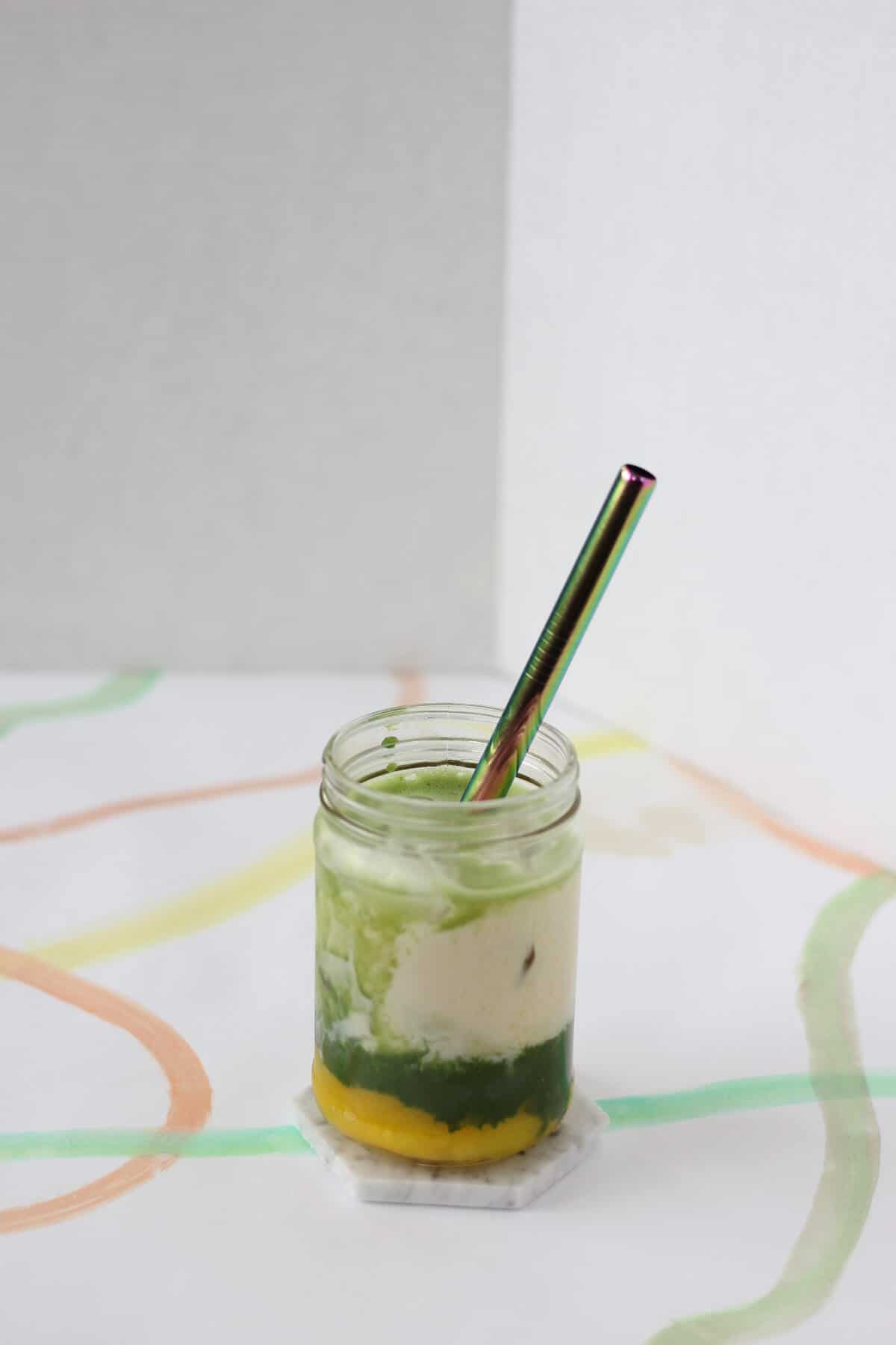 Clear glass with three layers of mango puree, matcha and milk.