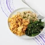 White plate with steamed rice, kimchi and scrambled eggs, and sauteed greens.