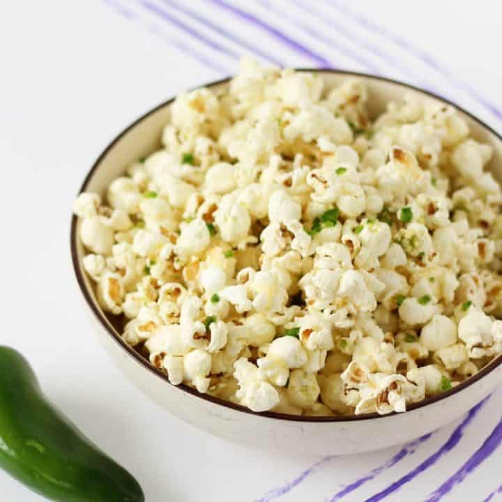 Bowl of yellow popcorn with small flecks of bright green jalapeno.