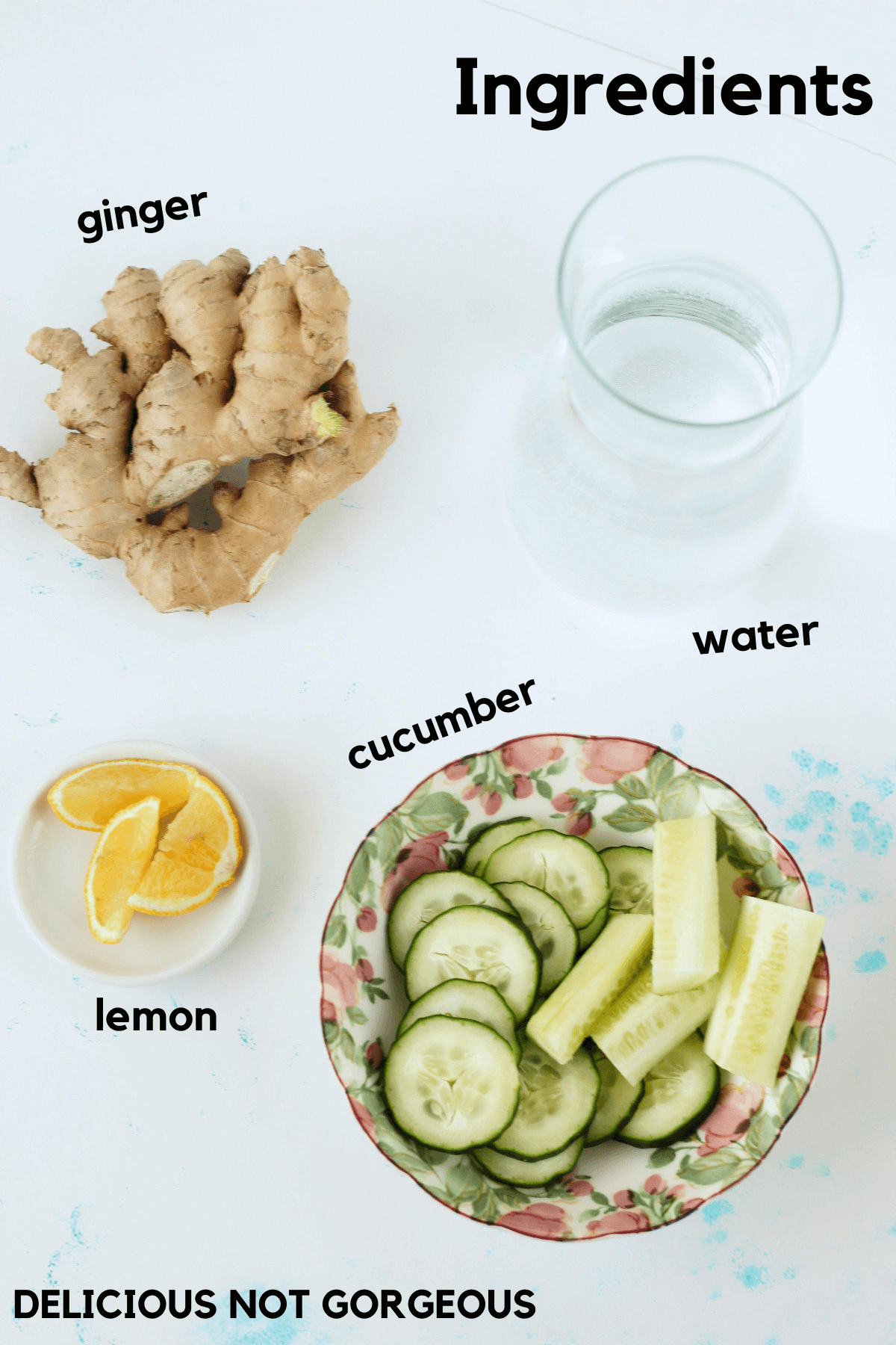 Ingredients laid out for the flavored water, including a pitcher of water, a bowl with cucumber spears and slices, lemon wedges, and some raw ginger root.